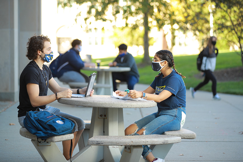 UToledo students sitting at an outdoor table with facemasks on